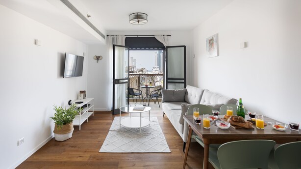 Un salon moderne avec un canapé, une table basse et un coin repas où l’on prend le petit-déjeuner.