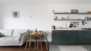 Un salon moderne comprenant un canapé, une table à manger et un coin cuisine avec des meubles verts et un plan de travail.