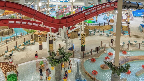 Ein Indoor-Wasserpark mit einer roten Rutsche, mehreren Pools und verschiedenen Wasserspielbereichen.
