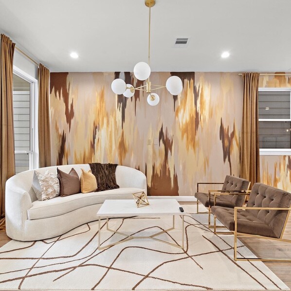 Relax in this stylish living room with a white sectional sofa, tufted armchairs, and a geometric coffee table.