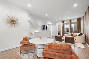 Relax in this stylish living room with a white sofa, two armchairs, and a flat-screen TV.