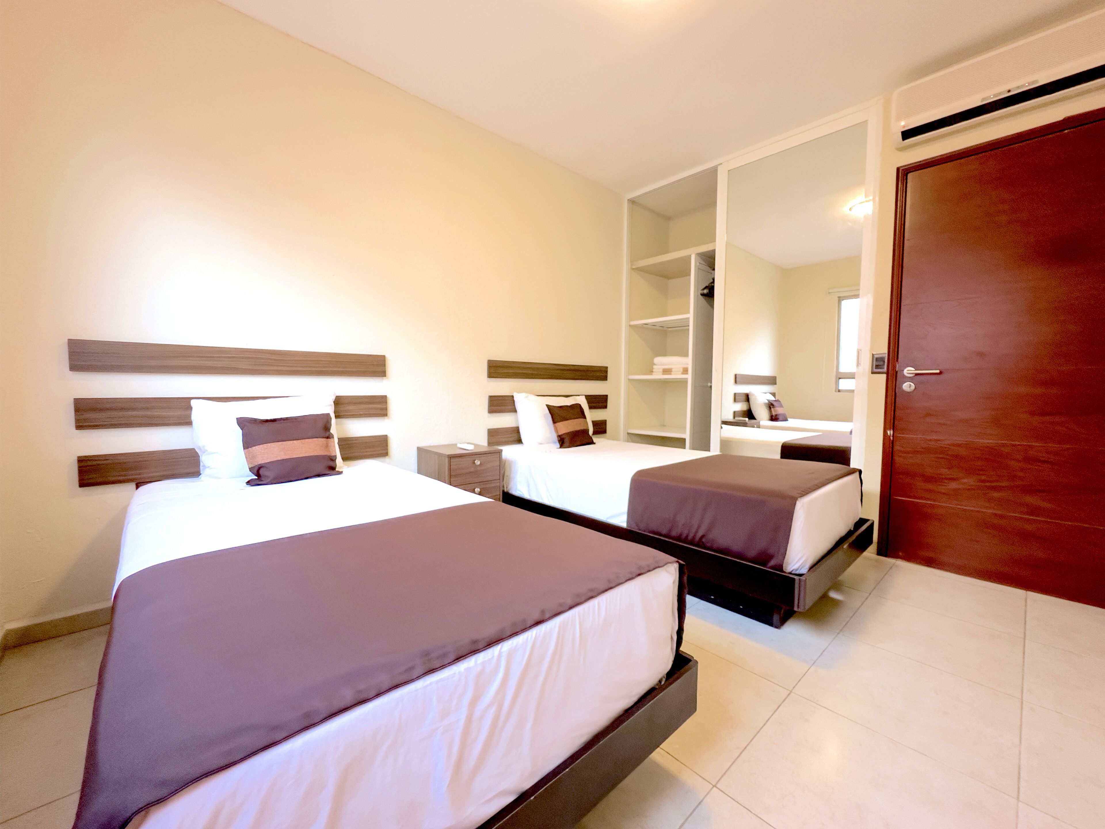 Ein Hotelzimmer mit zwei Betten, einem Kleiderschrank und einem Spiegel.