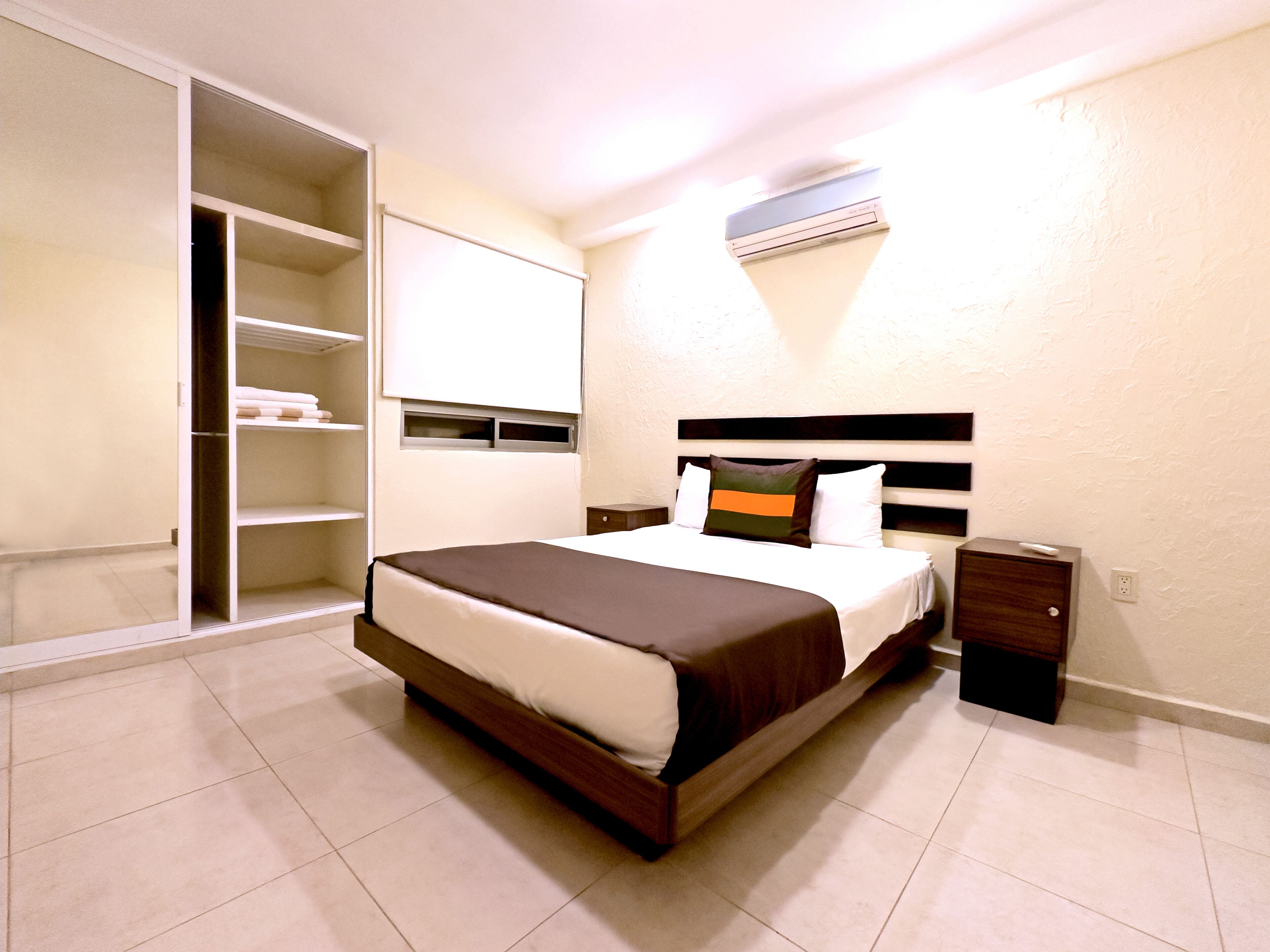 A neatly arranged bedroom with a large bed, a wardrobe, and a bedside table.