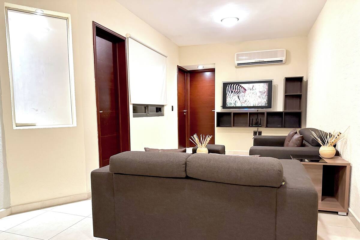 A modern living room with a sofa, a flat-screen TV, and a decorative vase.