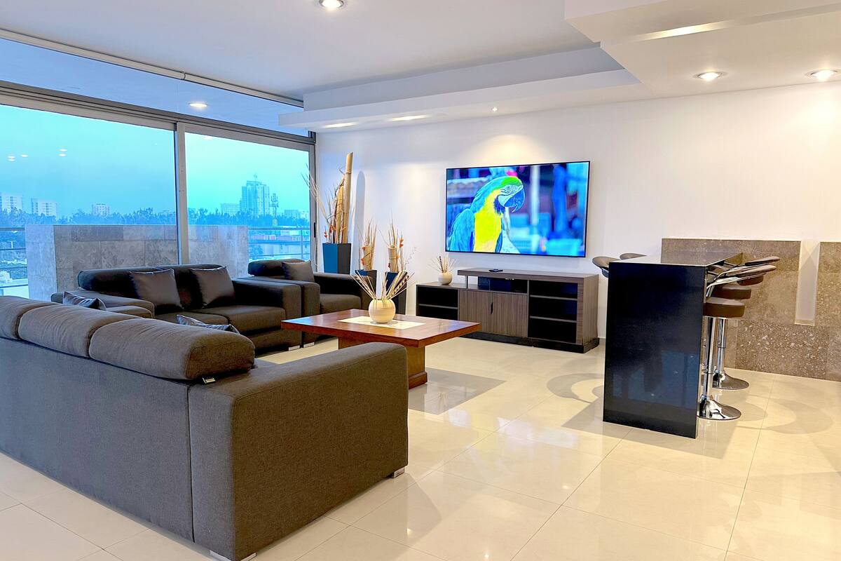A modern living room with a large flat-screen TV, a sofa, a coffee table, and a minimalist design.