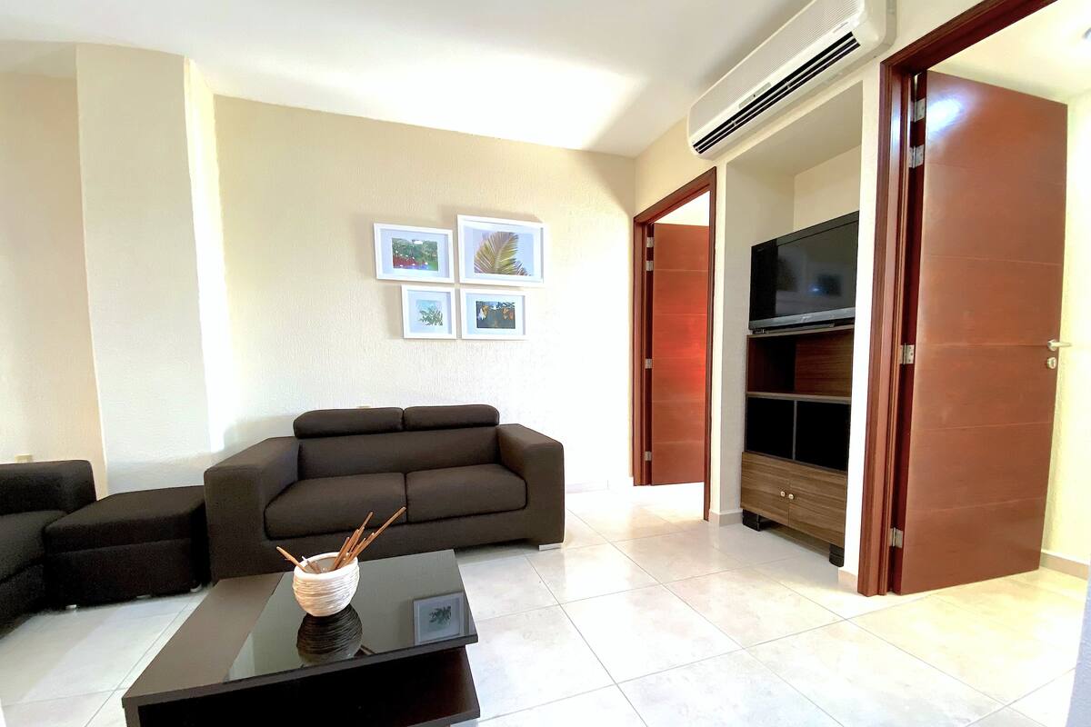 A modern living room with a sofa, a coffee table, and a TV stand.