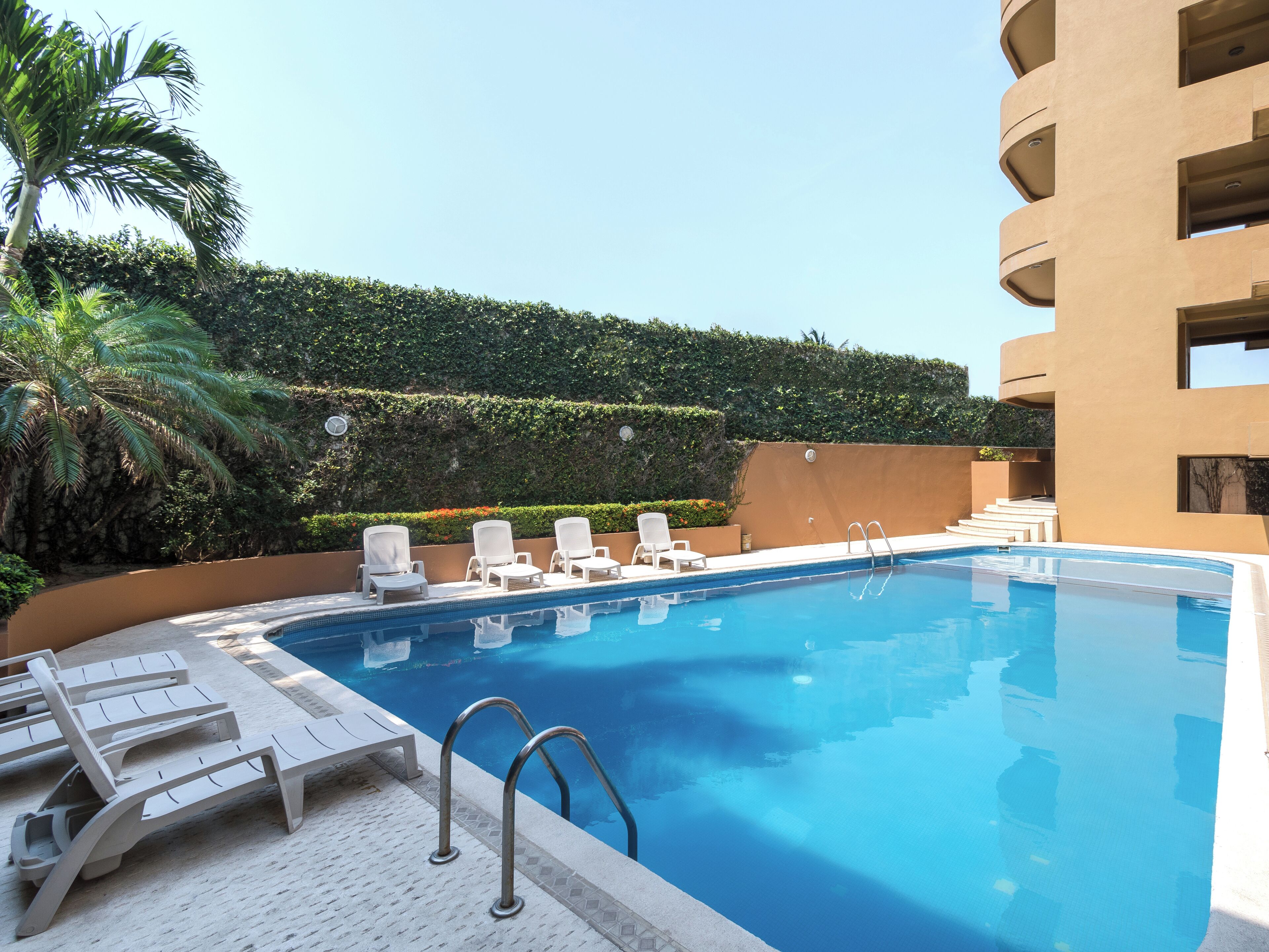 A swimming pool with lounge chairs and a staircase leading to a building.
