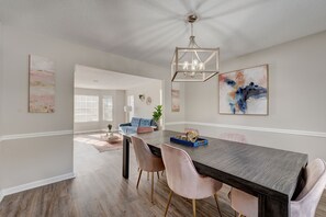 A dining area with a dark wood table, pink chairs, and a chandelier.