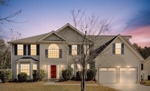 A two-story house with a red front door, multiple windows, and a garage. - Modern Family Fun Home near Stone Mountain (Decatur)