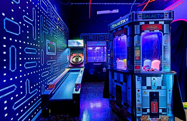 A row of arcade machines with neon lights and a futuristic design.
