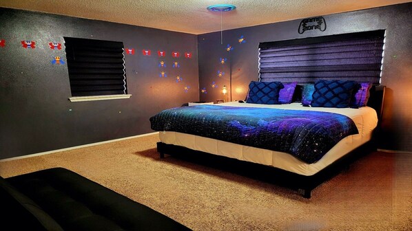 Un dormitorio con cama, ventana y pared decorada con temática de juegos.