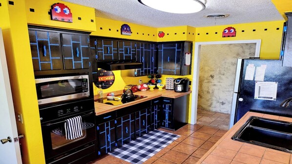 A kitchen with yellow walls, black cabinets, and a checkered floor.