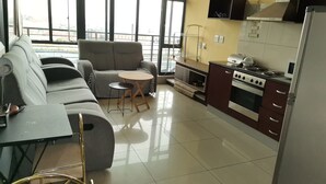 Una sala de estar moderna con un sofá, una mesita redonda y una cocina con estufa y armarios.
