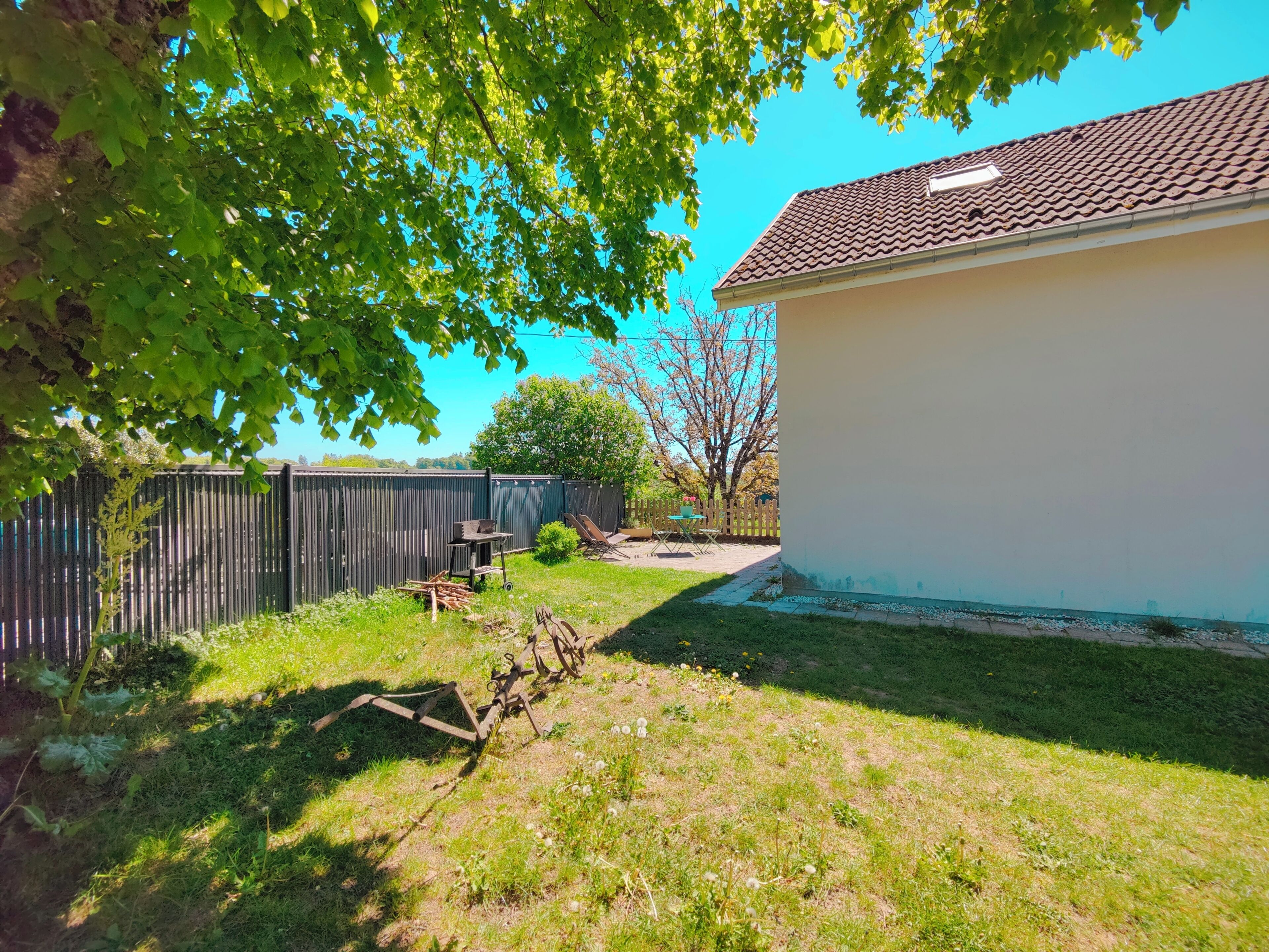 Ein Garten mit Holzzaun, Gartenhaus und Rasenfläche.