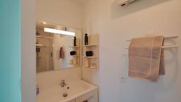 A bathroom with a mirror, a sink, a towel rack, and a shower.