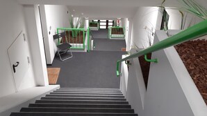 Una escalera con escalones negros y barandillas verdes que conduce a un rellano con una puerta y una planta pequeña.