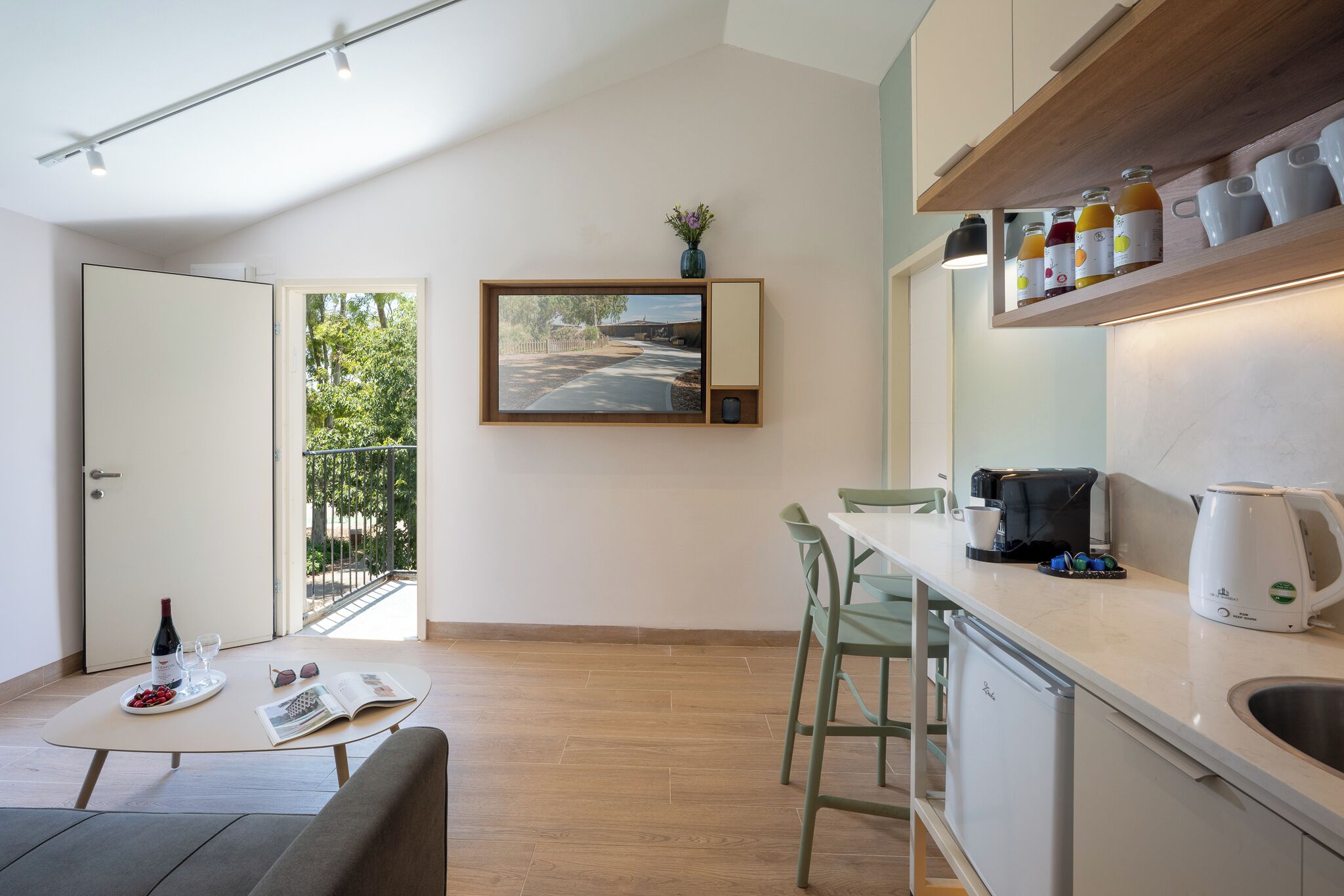 A modern kitchen with a dining area, a coffee machine, and a view of the outdoors.