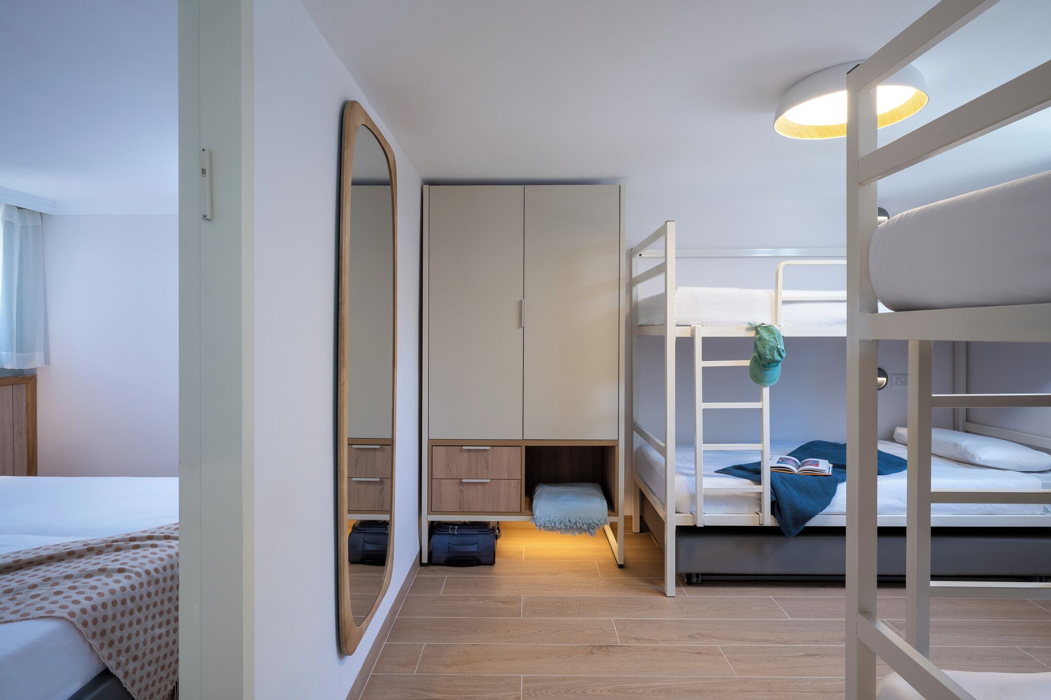 Een slaapkamer met stapelbedden, een kledingkast, een spiegel en een nachtkastje.