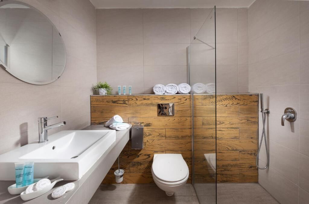 Un baño moderno con tocador de madera, un espejo grande, un lavabo blanco y cabina de ducha con paredes de vidrio.