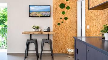 Una cocina moderna con un revestimiento de madera, un televisor de pantalla plana, una mesa de madera con taburetes y un mueble de color oscuro.
