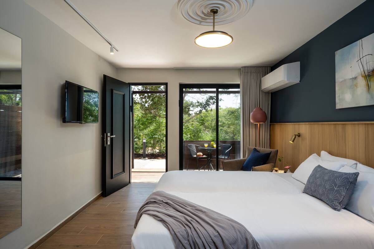 Habitación de hotel moderna con una cama grande, un televisor de pantalla plana, una lámpara en el techo y vistas al exterior.