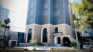 A modern building with a unique perforated facade, large arched windows, and a sign for "The Royal Inn." - Historia Royal (Udaipur)