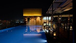 A rooftop pool with a view of a building with arched doors and a balcony. - Historia Royal (Udaipur)