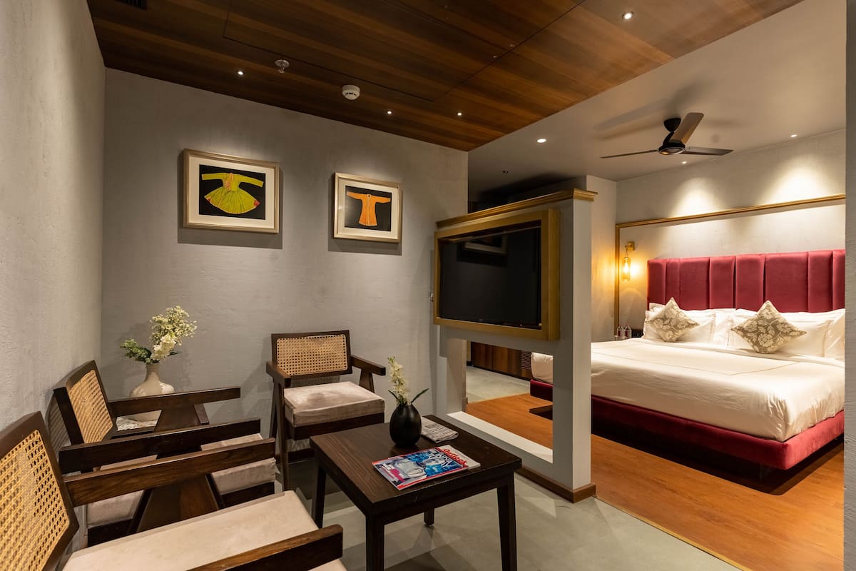 A hotel room with a bed, a TV, a desk, and two chairs.