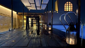 A wooden deck with a metal railing, lanterns, and a view of the city at night. - Historia Royal (Udaipur)
