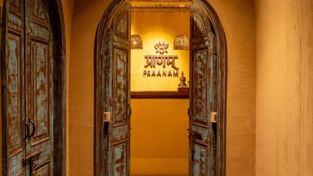 An arched hallway with rustic wooden doors and two lanterns. - Historia Royal (Udaipur)