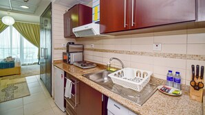 A modern kitchen with stainless steel appliances, a granite countertop, and wooden cabinets. - Gld - Cozy Studio with balcony (Dubai)