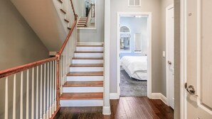 Un escalier avec des marches en bois et des rampes blanches menant à une chambre à coucher qui contient un lit et une fenêtre.