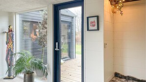 A room with a sliding glass door leading to an outdoor deck, a potted plant, and a framed picture on the wall.