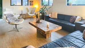 A modern living room with a wooden coffee table, leather sofas, and a fluffy chair.