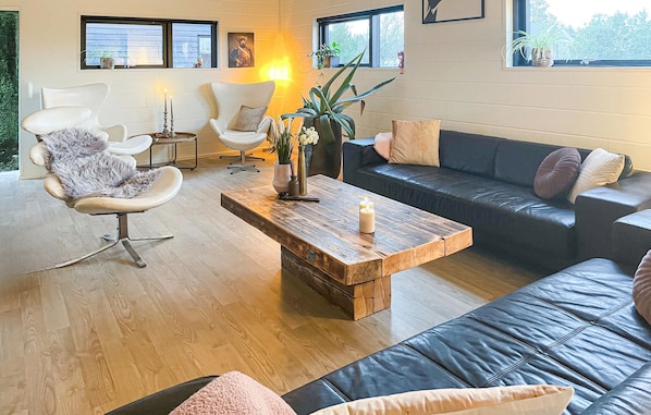 A modern living room with a wooden coffee table, leather sofas, and a fluffy chair.
