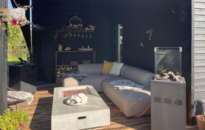 A modern outdoor living space with a sofa, a coffee table with snacks, a grill, and a fish tank.