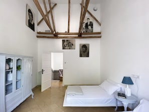 A bedroom with a bed, a nightstand, a cabinet, and wooden beams on the ceiling. - Orchard of the Purisima (Santa Fe)