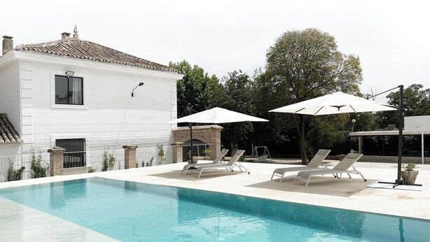 A swimming pool with lounge chairs and umbrellas, a white house with a tiled roof, and a garden area. - Orchard of the Purisima (Santa Fe)