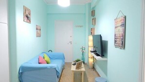 Een kleine, goed verlichte kamer met een enkel bed, een bureau met een computer, een televisie en een poster aan de muur.