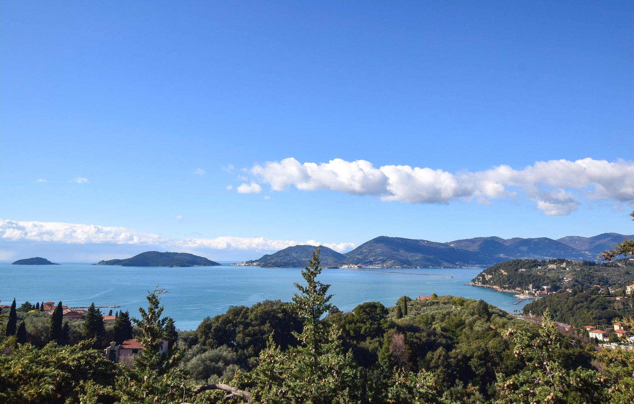 Un paysage côtier offrant une vue dégagée sur la mer, les montagnes et une végétation luxuriante.