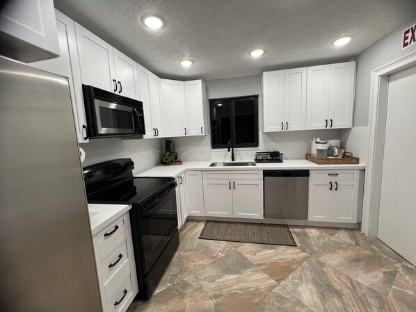 A modern kitchen with white cabinets, a black stove, a microwave, and a dishwasher.
