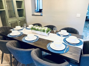 Enjoy meals in this stylish dining area with a long table, comfortable chairs, and a touch of greenery.