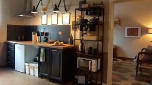 A modern kitchen with a central island, black cabinets, and a microwave shelf. - TRASTEVERE BOUTIQUE (Roma)