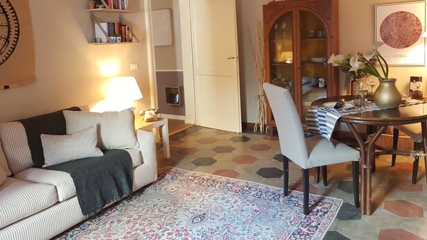 A living room with a sofa, a coffee table, a dining table with chairs, a bookshelf, and a cabinet. - TRASTEVERE BOUTIQUE (Roma)