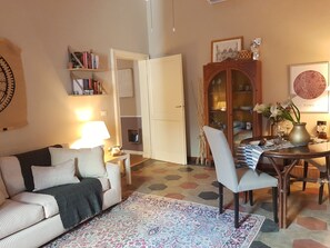 Un salon comprenant un canapé, une table basse, une table à manger avec des chaises, une bibliothèque et un meuble de rangement.