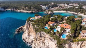 A coastal resort with multiple buildings, a beach, and a cliff overlooking the sea. - Plaça de sa Punta, 4, 07750 Cala Galdana, Balearic Islands, Spanyolország (Cala Galdana)