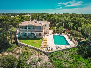 Ein großzügiges Haus mit Swimmingpool, überdachter Terrasse und üppigem Garten.