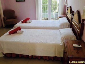 A hotel room with two beds, a chair, a bedside table with a remote control, and a window with a view of greenery. - Plaça de sa Punta, 4, 07750 Cala Galdana, Balearic Islands, Spanyolország (Cala Galdana)