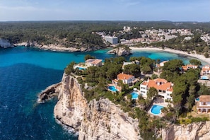 A coastal resort with multiple buildings, a beach, and a cliff overlooking the sea.