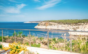 A coastal view with a rocky cliff and a clear blue sea.